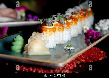 Plato de sushi rolls con decoración de especias de cerca sobre fondo de madera negra Foto de stock