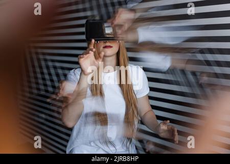 Chica que hace gestos con auriculares de realidad virtual Foto de stock