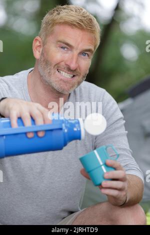 hombre vertiendo agua en un vaso de plástico Foto de stock