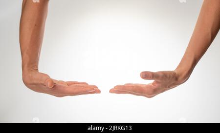 Las manos de las mujeres aisladas sostienen un objeto grande sobre un fondo blanco. Fotografía de alta calidad Foto de stock