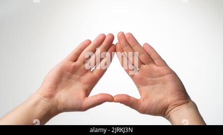 Las palmas del hombre están dobladas en un triángulo sobre un fondo blanco. Fotografía de alta calidad Foto de stock