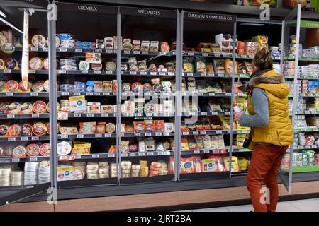 Mostrador de quesos en un supermercado Super U. Mujer haciendo algunas compras Foto de stock