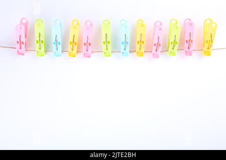 Chinchetas de ropa de colores sobre cuerda aisladas sobre fondo blanco Foto de stock