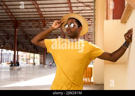 Hombre guapo de moda con sombrero y gafas de sol en una camisa de