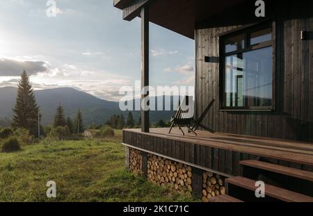 Sillas de madera negra en la terraza con vistas a la montaña al atardecer Foto de stock