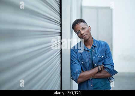 Retrato de un hombre africano apoyado en una muralla urbana en la calle Foto de stock