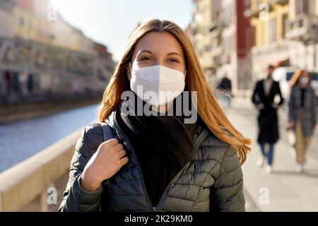 Belleza moda niña con máscara protectora de cara caminando en la calle de la ciudad al atardecer Foto de stock