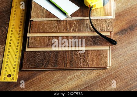 Piso Laminado tablones y herramientas sobre fondo de madera Foto de stock
