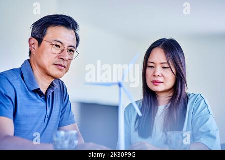 Hombre y mujer maduros examinando el modelo de aerogenerador en casa Foto de stock