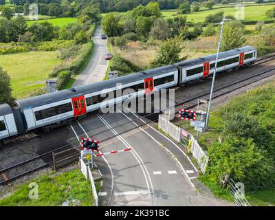 Bonvilston, Vale of Glamorgan, Gales - septiembre de 2022: Vista aérea de un tren de cercanías que pasa por un cruce de nivel en las afueras de Cardiff. Foto de stock
