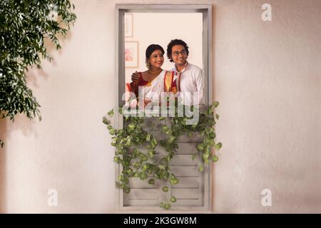 Una pareja bengalí de pie junto a la ventana y mirando al exterior Foto de stock