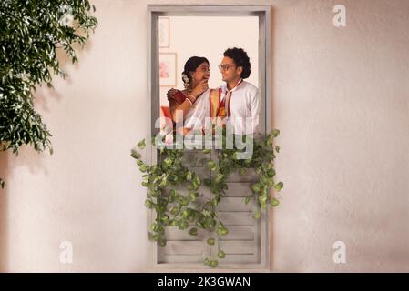 Feliz pareja bengalí de pie junto a la ventana Foto de stock