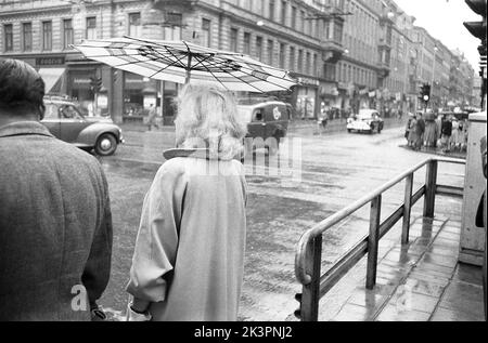Paraguas en la 1950s. La lluvia está derramando y se ve a una mujer sosteniendo un paraguas sobre sí misma. Es un día lluvioso en Estocolmo Suecia 1953. Ref 2A-1 Foto de stock