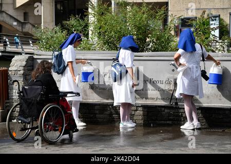 Lourdes, Hautes-Pyrénées, Francia. Peregrinos cristianos recogiendo el agua de Lourdes que brota de la Gruta de Massabielle en el Santuario de Nuestra Señora Foto de stock