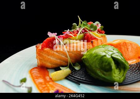 Filete de salmón con tomates confitados y espárragos verdes con espaguetis negros, salsa Pesto y sorbete de zanahoria y maracuyá Foto de stock
