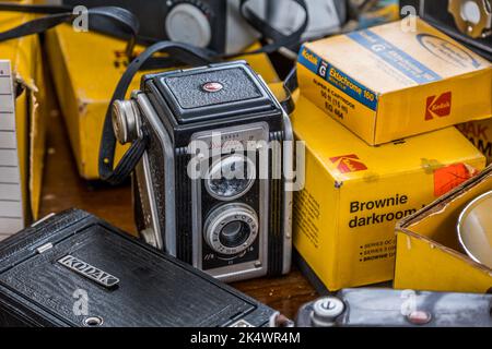 Una cámara réflex de doble objetivo Kodak en el centro rodeada de otros consumibles Kodak y vista parcial de otras cámaras agrupadas Foto de stock