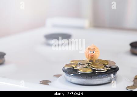 el concepto de ahorrar el cerdo pequeño del juguete del money .a está en las monedas que mienten en el quemador del gas. Foto de stock
