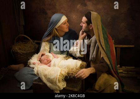 Pareja que representa una escena de Navidad en vivo con su bebé recién nacido de 8 días Foto de stock
