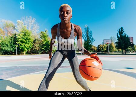 Joven Mujer afroamericana en vestimenta deportiva rebotando una