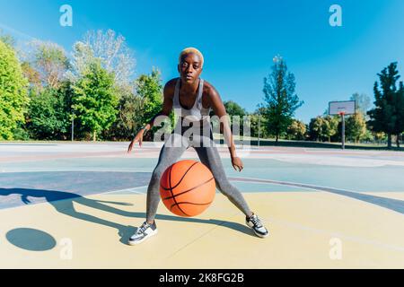 Joven Mujer afroamericana en vestimenta deportiva rebotando una