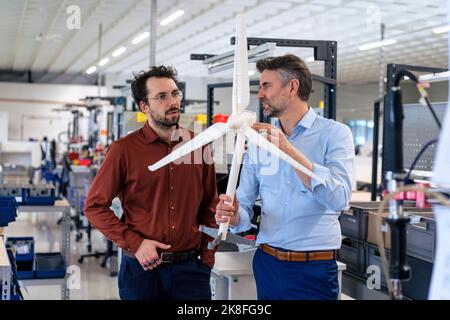Hombre de negocios maduro con un compañero que examina el aerogenerador en el almacén Foto de stock