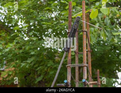 Un soplete de soldadura colgando de la columna del inducido - concepto de construcción. Fondo de naturaleza verde. Foto de stock