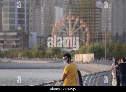 Un hombre iraní con una máscara facial protectora mira mientras se encuentra de pie en el complejo recreativo del lago artificial Chitgar en el noroeste de Teherán, tras el brote de COVID-19 en Irán, el 13 de agosto de 2020. Las personas que viven en Teherán parecen estar acostumbradas al nuevo coronavirus y usan la máscara como rutina diaria. (Foto de Morteza Nikoubazl/NurPhoto) Foto de stock