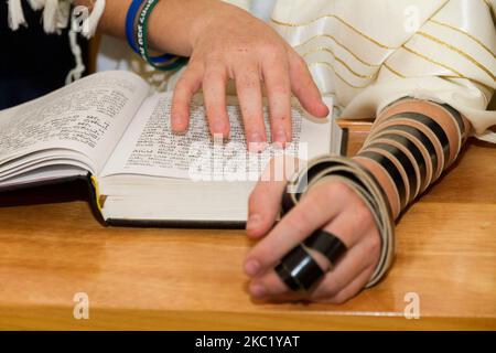 Un joven señalando una frase en un libro bíblico (sefer torah), mientras lee una oración en un ritual judío (ceremonia de Bar Mitzvah) Foto de stock