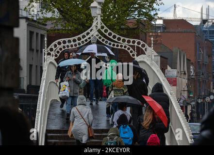La gente camina sobre el puente Ha'Penny en el centro de la ciudad de Dublín durante la lluvia el martes 18 de mayo de 2021, en Dublín, Irlanda. (Foto de Artur Widak/NurPhoto) Foto de stock