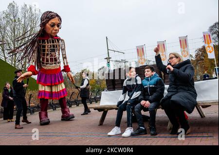 Una mujer está hablando con un par de niños de Siria, mientras que el títere gigante 'Little Amal', una niña de nueve años refugiada en Siria y más de 11 pies de altura, los observa en las afueras del parque en miniatura, Madurodam, en La Haya, el 15th de noviembre de 2021. (Foto de Romy Arroyo Fernandez/NurPhoto) Foto de stock