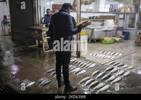 Un hombre iraní que lleva pan, mira peces mientras se levanta de una piscifactoría en la aldea de Dastak cerca de la ciudad de Lahijan 347Km (216 millas) al norte de Teherán en la provincia de Gilan durante las vacaciones de Año Nuevo Iraní dos años después del brote de la enfermedad COVID-19 en Irán el 23 de marzo, 2022. (Foto de Morteza Nikoubazl/NurPhoto) Foto de stock