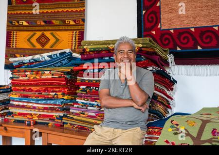 Maestro tejedor Jerónimo Vásquez G. con alfombras de lana en el negocio de tejer familiar en Teotitlan, Oaxaca, México. El hilo se tiñe con todo el tinte natural Foto de stock