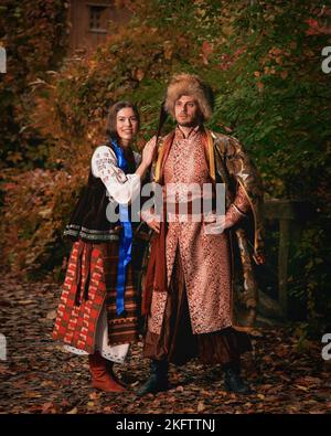 Joven pareja sonriente vestido ropa tradicional ucraniana. Hombre y mujer cosacos con disfraces bordados al aire libre. Conjunto vintage Foto de stock