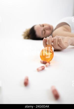 Escena de una chica acostada en el suelo con una sobredosis de pastillas (enfoque selectivo intencional) Foto de stock
