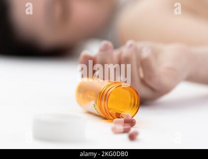 Escena de una chica acostada en el suelo con una sobredosis de pastillas (enfoque selectivo intencional) Foto de stock