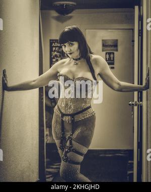 Un artista burlesque posa entre bastidores en un pasillo. Foto de stock