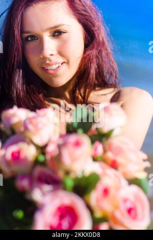 En un signo de afecto Cuidado y amor UN bonito La mujer entrega un regalo floral en forma de Un ramo de rosas para capturar el corazón de Su ADM Foto de stock