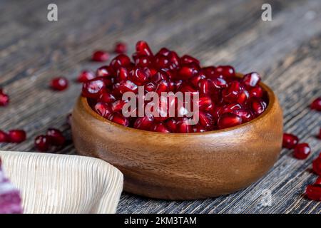 semillas de granada esparcidas sobre una tabla de madera, semillas de granada roja madura se dispersan sobre una tabla de madera Foto de stock