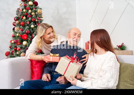 El abuelo dando una caja de regalo a una nieta feliz