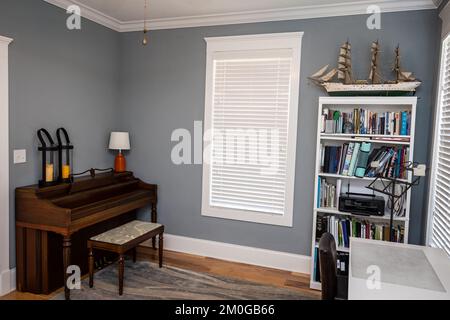 Sala de música casera para estudiantes con un piano de madera y paredes grises azules