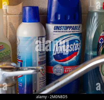 Londres. REINO UNIDO- 12.07.2022. Una botella de lejía de Domestos junto a un fregadero de la cocina, entre otros productos de limpieza para el hogar. Foto de stock
