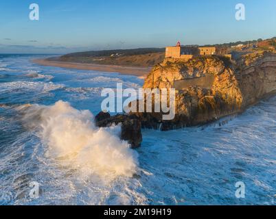 Faro y grandes olas en Nazare Foto de stock