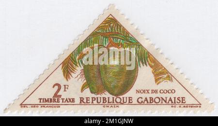 GABÓN - 1962 de diciembre de 10: Un sello postal multicolor de 2 francos que representa Cocos. La palma de coco es omnipresente en las regiones tropicales costeras y es un icono cultural de los trópicos. El cocotero (Cocos nucifera) es un miembro de la familia de las palmeras (Arecaceae) y la única especie viva del género Cocos. El término 'coco' (o el arcaico 'cocoanut') puede referirse a toda la palma de coco, la semilla, o el fruto, que botánicamente es una drupa, no una nuez. El nombre proviene de la antigua palabra portuguesa coco, que significa 'cabeza' o 'gaviota' Foto de stock