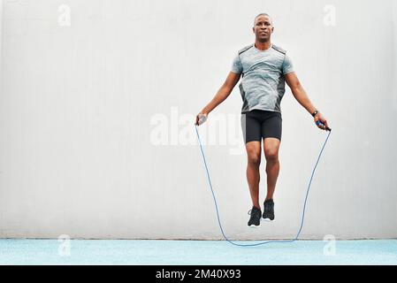 Pies rápidos, pies rápidos. Retrato completo de un joven atleta guapo usando una cuerda durante una sesión de entrenamiento al aire libre. Foto de stock