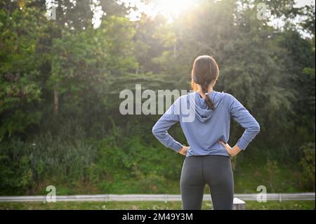 Vista trasera, Una mujer asiática sana en ropa deportiva estirando su  pierna antes de salir a correr en la calle del parque. Estilo de vida  saludable Fotografía de stock - Alamy