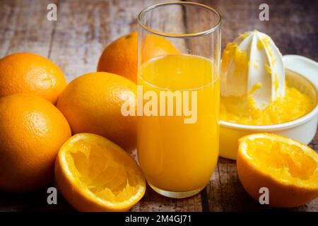 zumo de naranja recién exprimido en un vaso sobre un fondo de madera Foto de stock