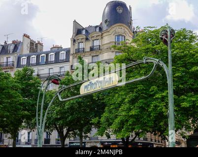 Lámparas Héctor Guimard y señal metropolitana en la entrada de metro Place de la Nation con el edificio Haussmann al fondo, París, Francia. Foto de stock