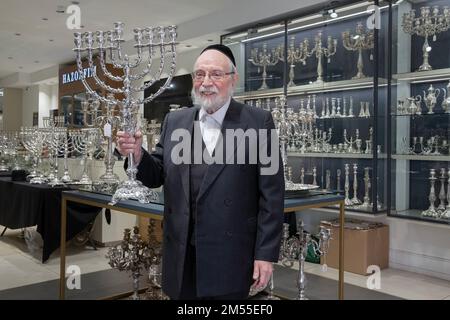 Portarit de un hombre judío ortodoxo que opera una tienda de venta de artículos religiosos de plata. Aquí está sosteniendo una hermosa menorah. En Brooklyn, Nueva York. Foto de stock