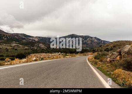 Un día nublado en el campo de Creta. Un camino que conduce a las montañas Foto de stock