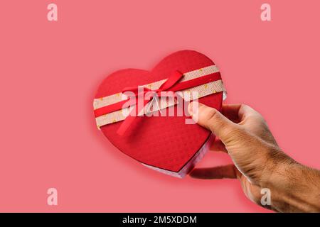 Corazón de San Valentín rojo en una mano de hombre en la pared azul de  fondo. Tarjeta de felicitación con copia espacio para el texto Fotografía  de stock - Alamy